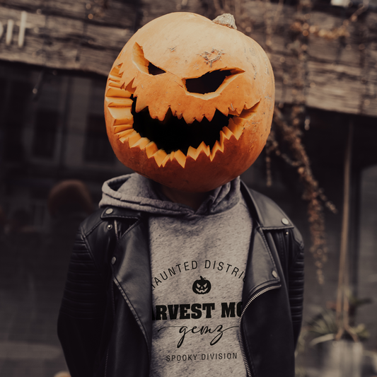 Person wearing a pumpkin head mask with a carved face, standing outdoors.