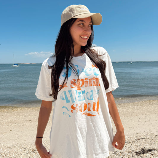 Woman wearing a white t-shirt with colorful text on a beach